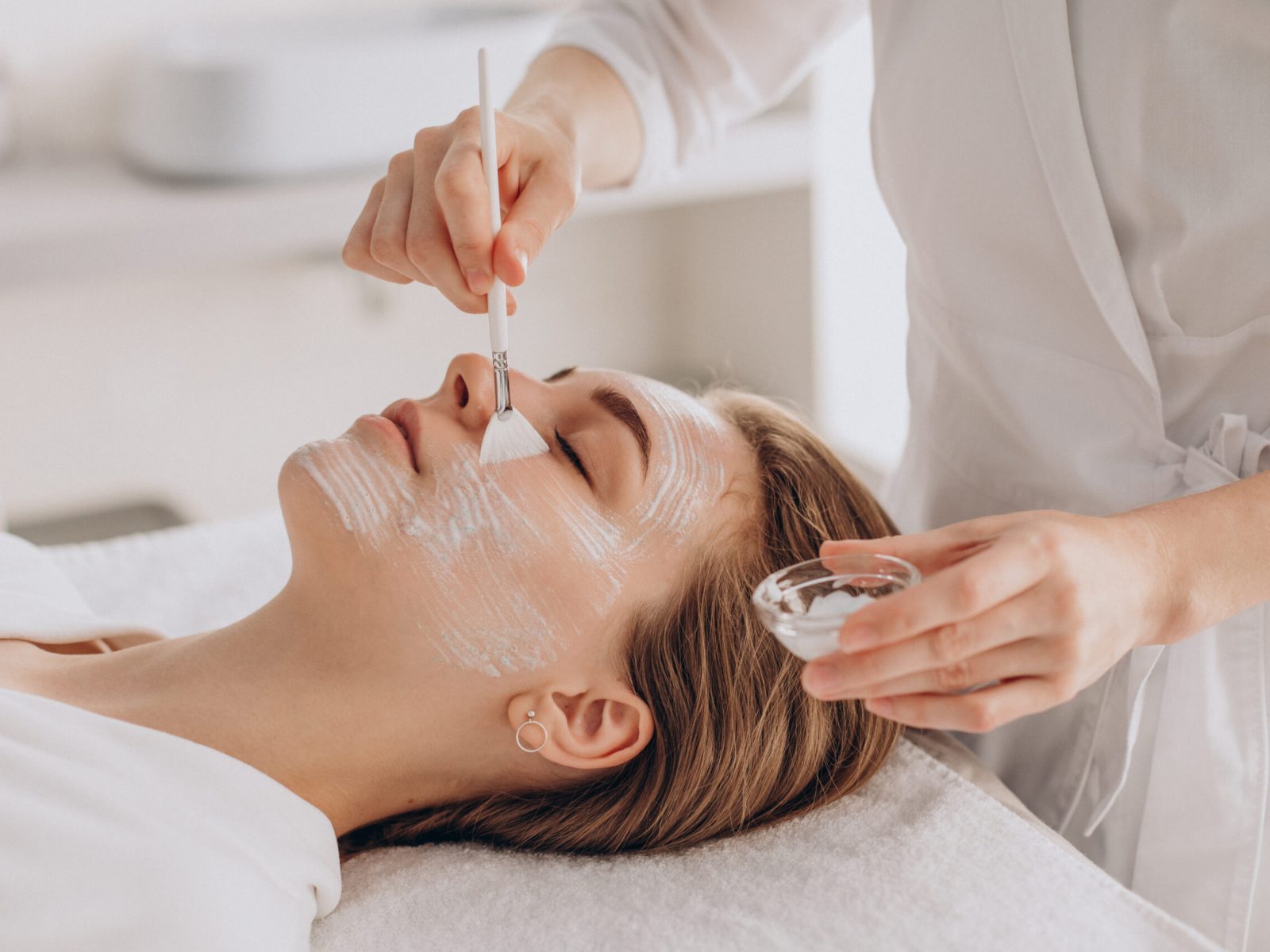Cosmetologist doing face treatment and applying face mask